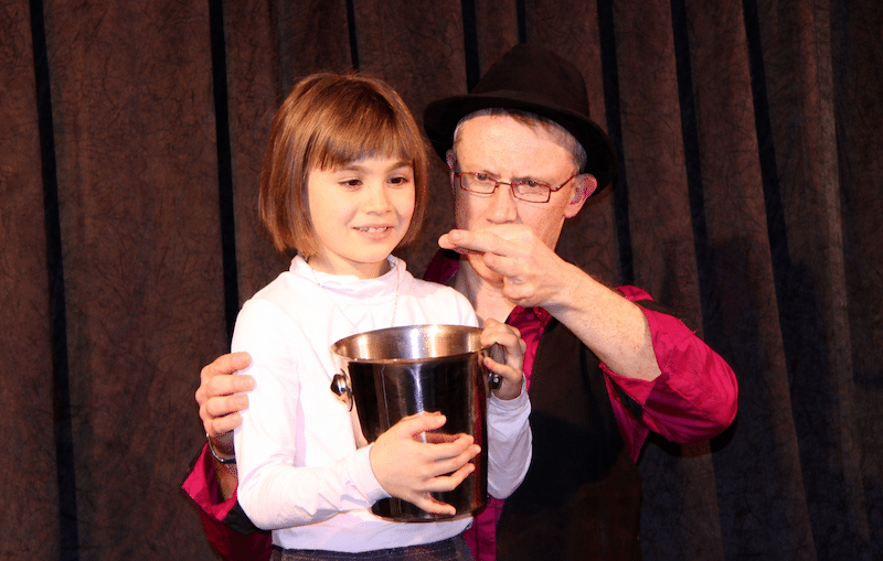 Chrystian Yann faisant participer une enfant sur scène lors d’un spectacle de magie interactif pour enfants